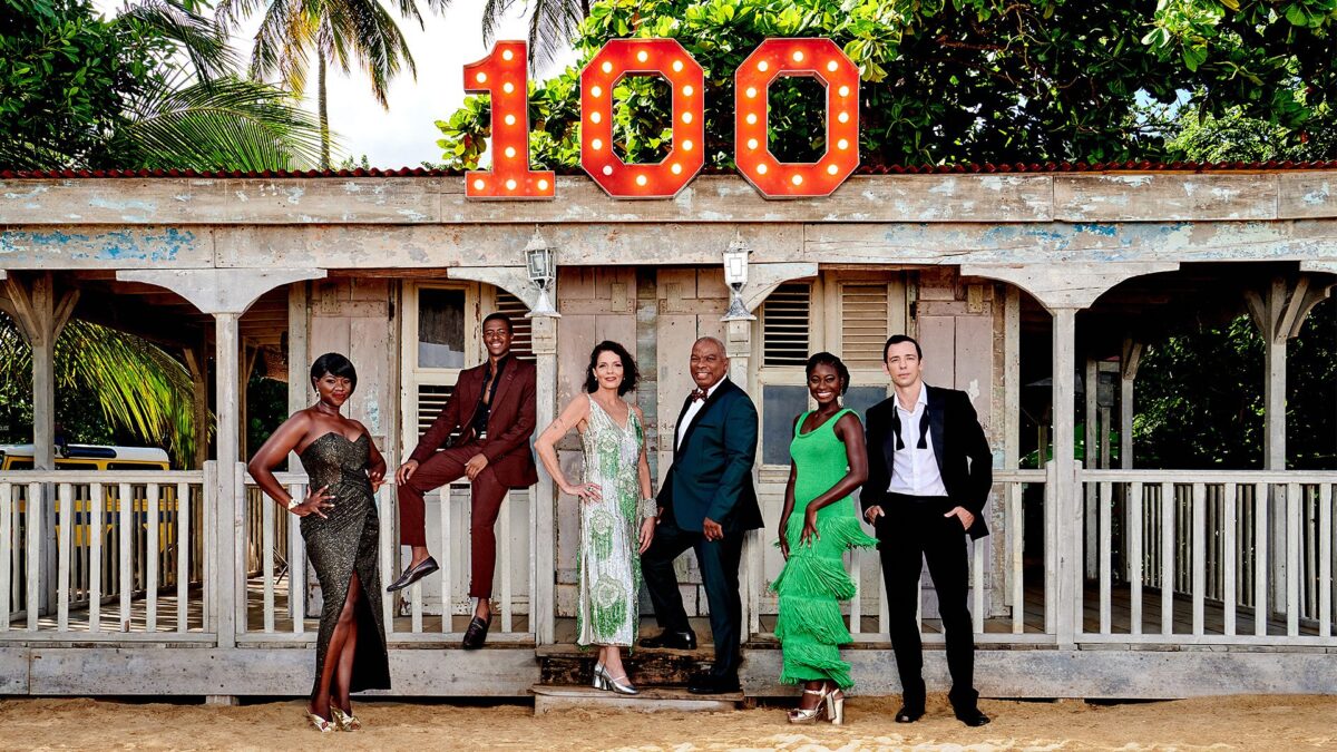 Death In Paradise cast group photo under '100' sign